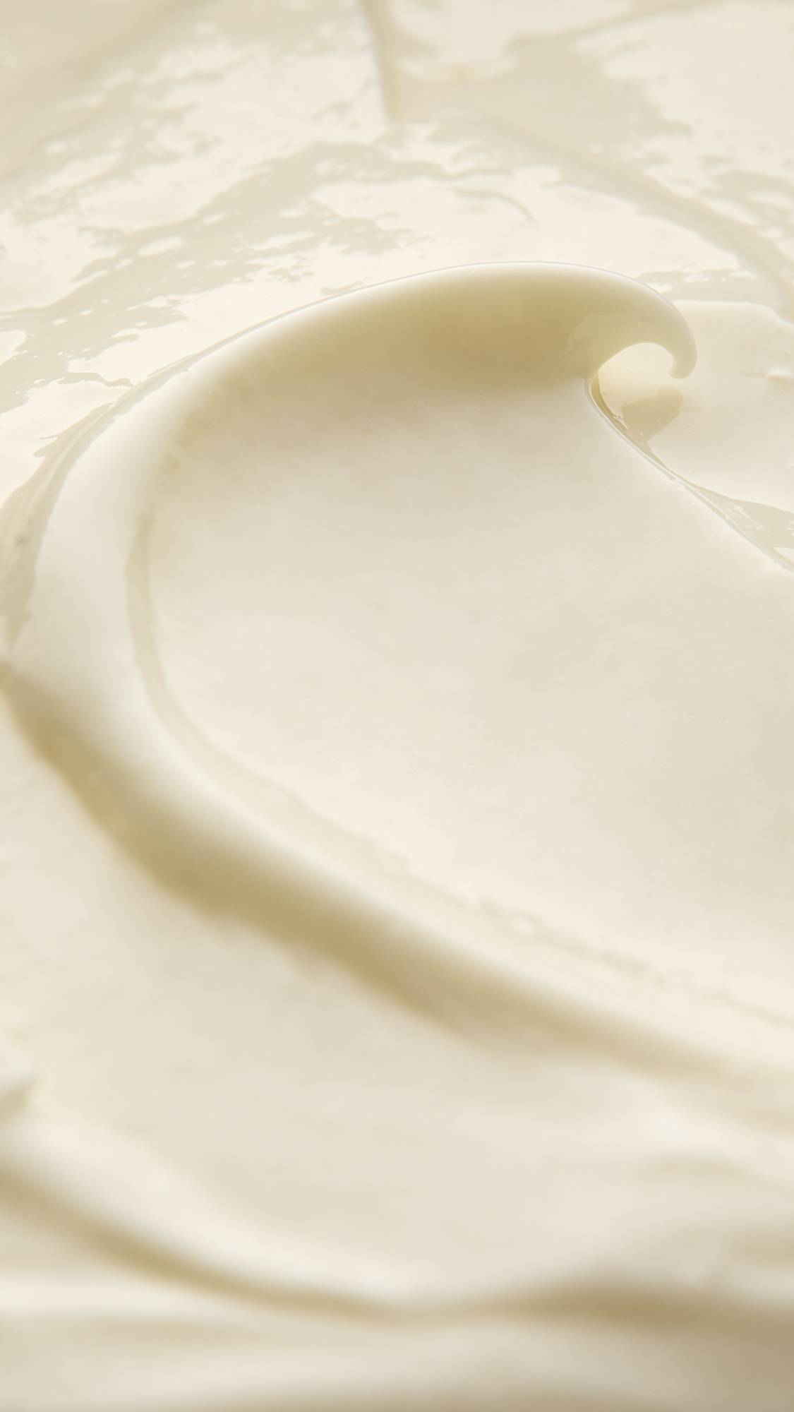 A super close-up of the Enzymion self-preserving moisturiser focusing on the thick, creamy consistency of the lotion showing a curled peak of lotion slicked through the product. 