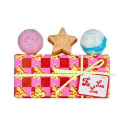 Fa La La. A rectangular gift box wrapped in pink and red checkered paper with the words "Fa La La" in retro letters. It is tied with a thin, yellow ribbon and gift tag. There are three bath bombs sitting on top of the box. 
