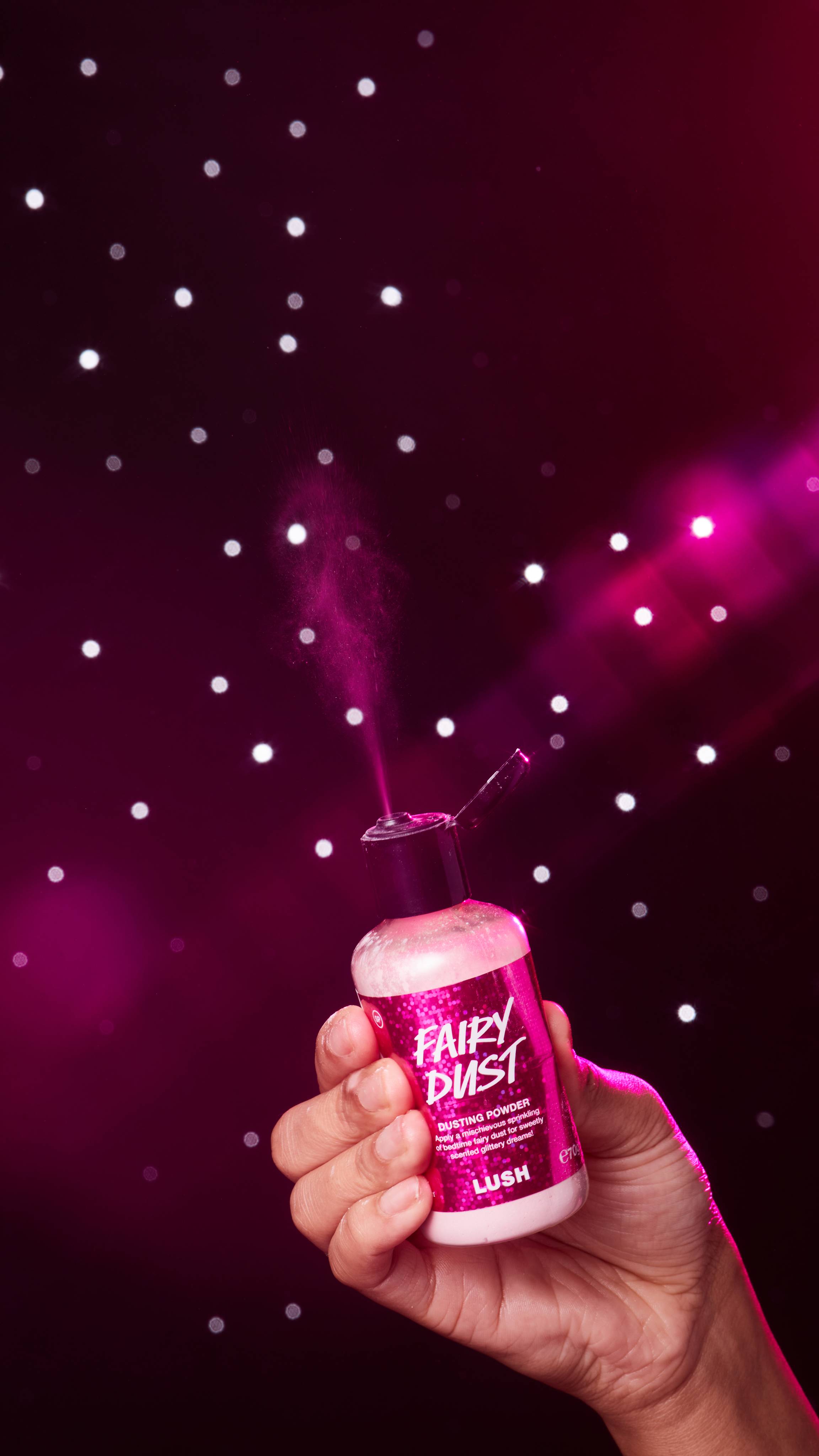 Image shows a close-up of the model's hand holding the Fairy Dust bottle as they squeeze some of the shimmering dust out. 