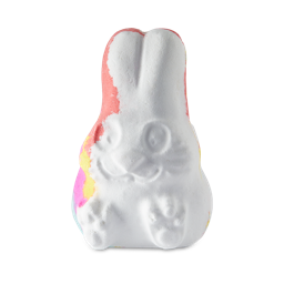 Follow The White Rabbit. A white bath bomb shaped like a sitting rabbit with ears pointed up and rainbow colours of pink, yellow orange and blue just peeking out at the edge.