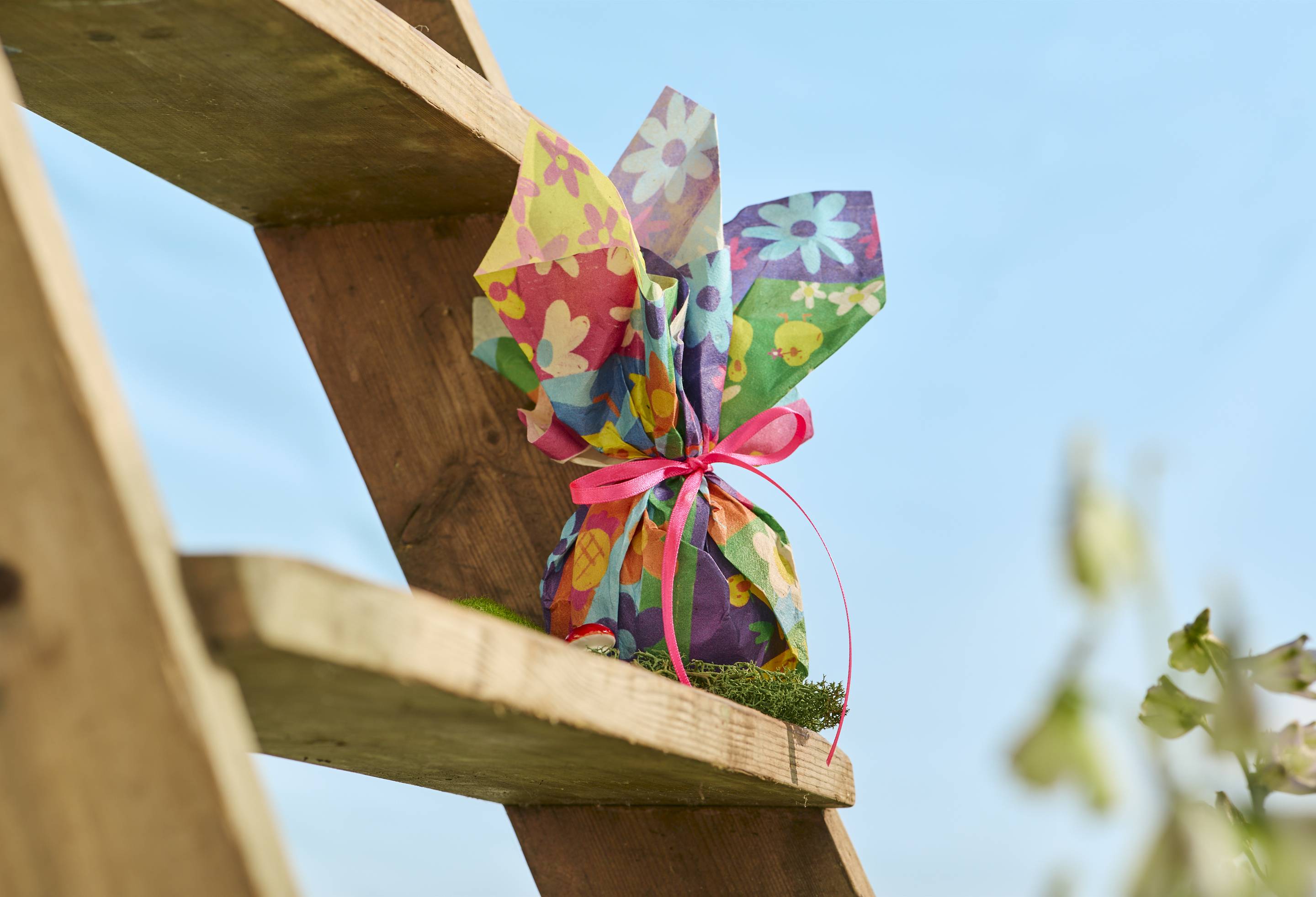 The image shows a close-up of a wooden ladder step. A bath bomb has been neatly wrapped in the Fresh As A Daisy lokta wrap and tied with a bow sitting on a step. 