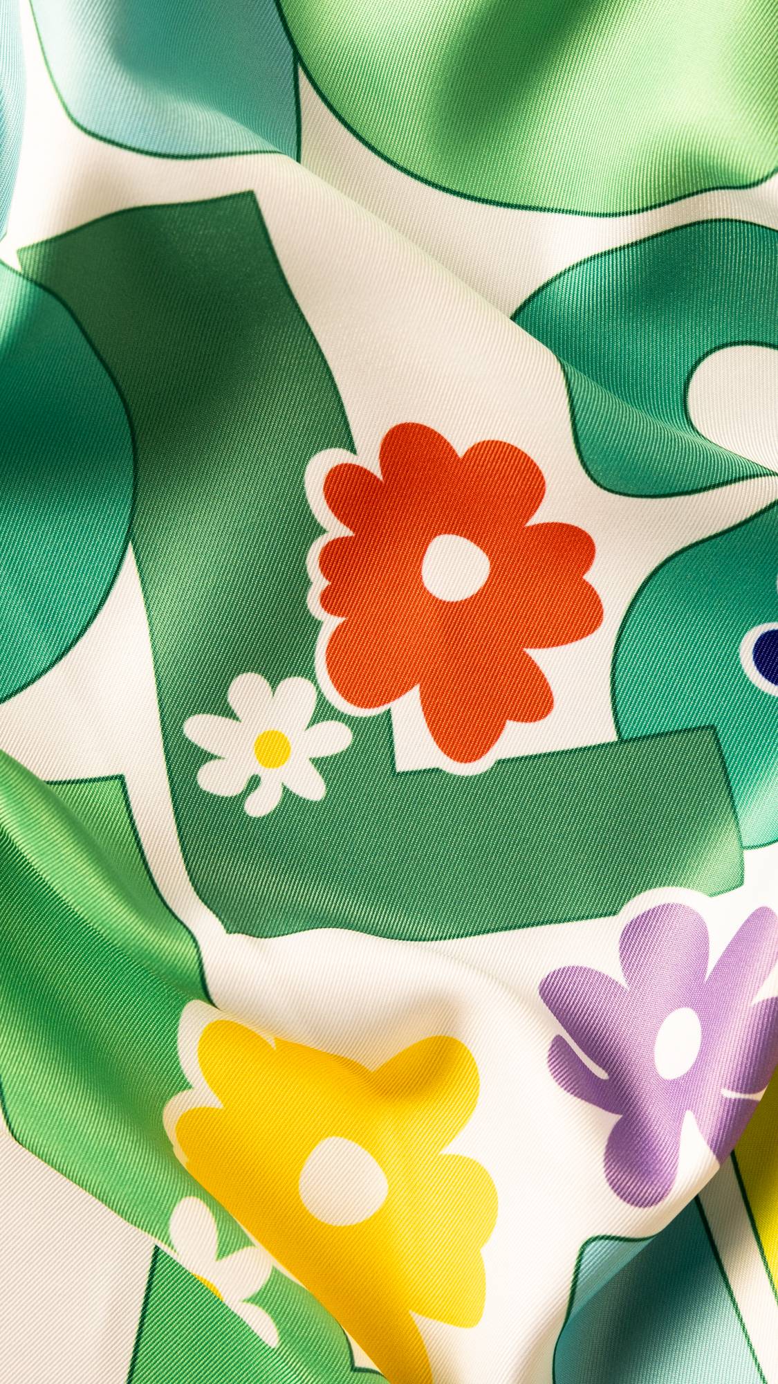 Image shows a super close-up of the knot wrap, focusing on the green lettering with orange, yellow and purple flowers.