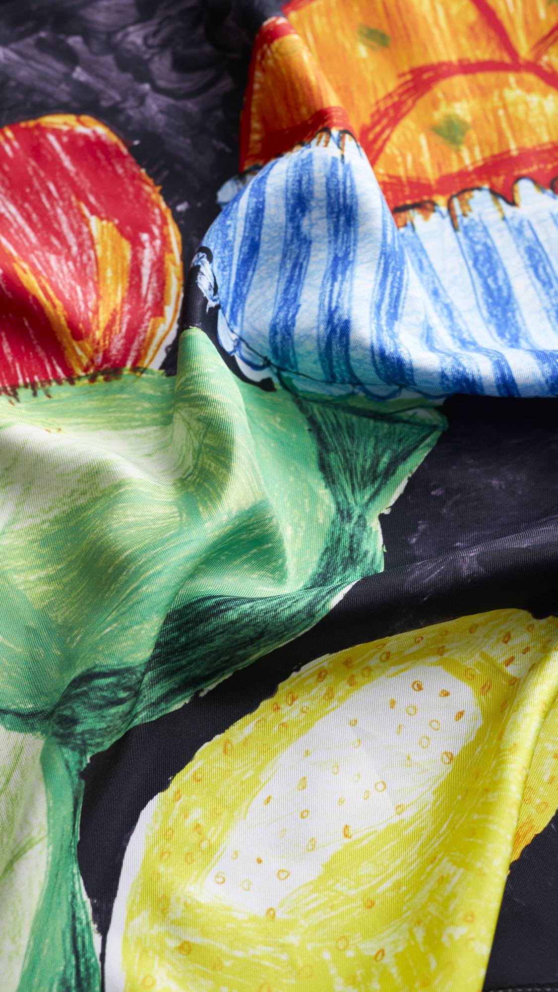 The image shows a close-up of the Fruit Fest knot wrap focusing on the folds and sheen of the fabric. 