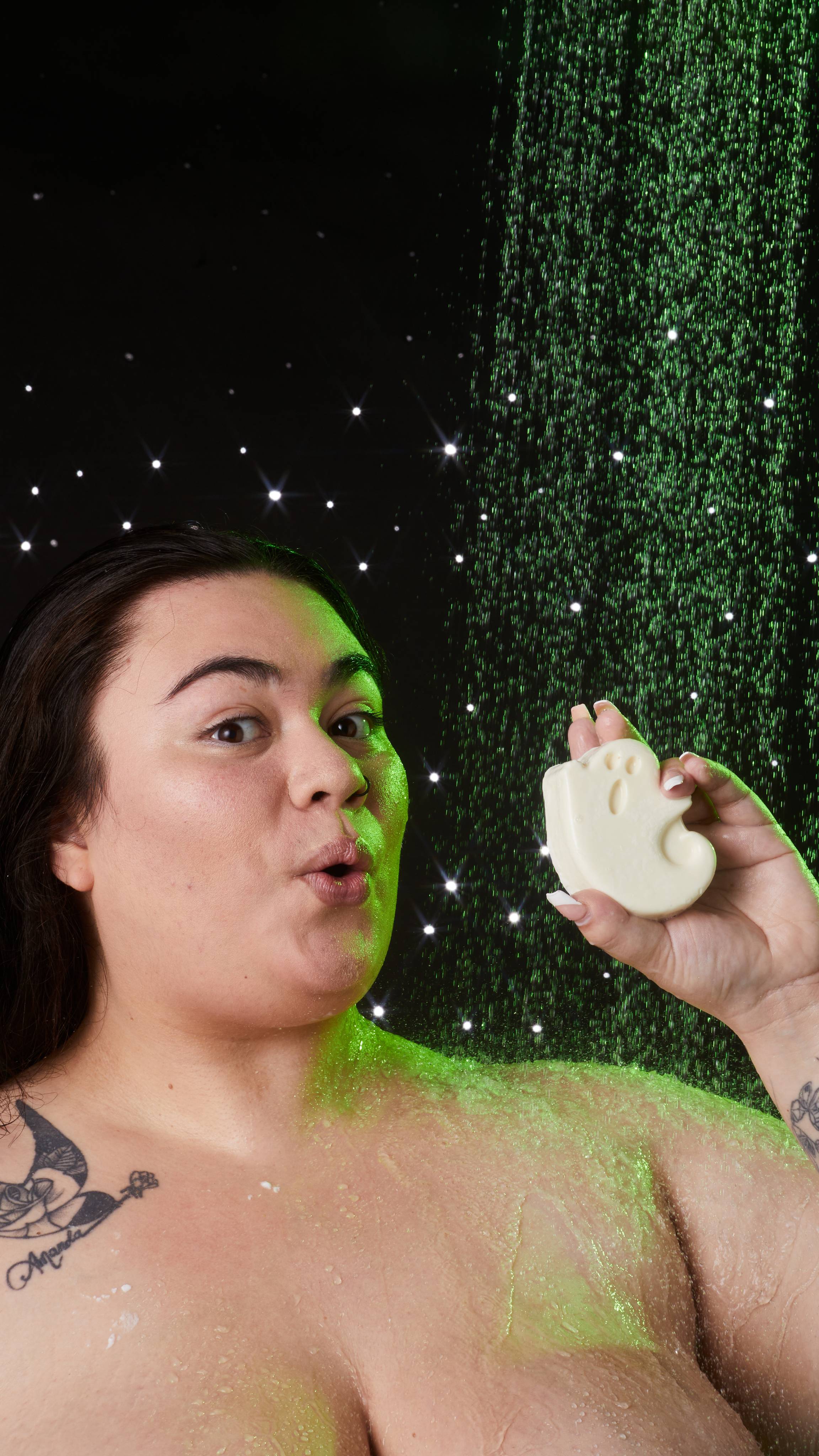 Model is in the shower holding the Ghost in the Dark soap up by their face where they are making a fun, shocked face.