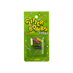 Glitter Bombs Brights. Five, small, cylindrical, pill-shaped, transparent casings filled with different coloured glitters. The packaging is bright green with illustrated pills bouncing. The Text reads: "Glitter Bombs Brights Glitter Crumble".