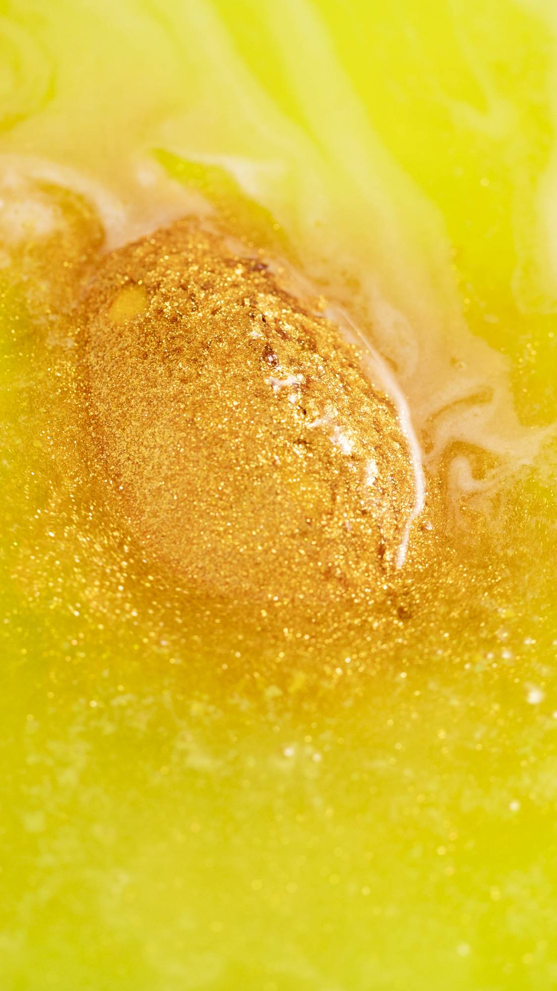 The Golden Egg bath bomb is dissolving in the bath watering giving off bright neon-yellow waters sprinkled with golden glitter throughout. 