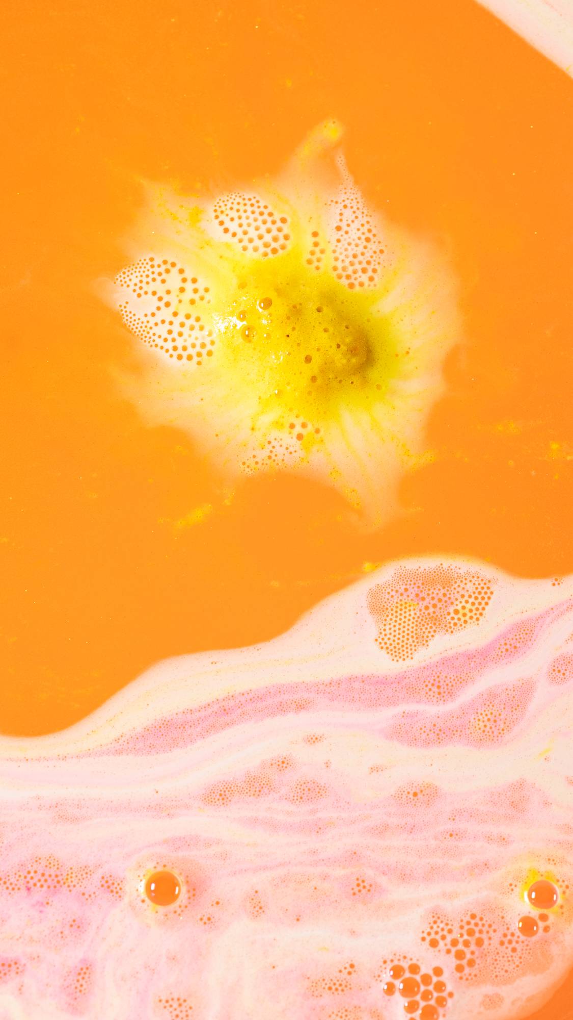 The Golden Egg bath bomb melt has almost dissolved leaving a sea of orange water with a small flash of yellow foam remaining. 