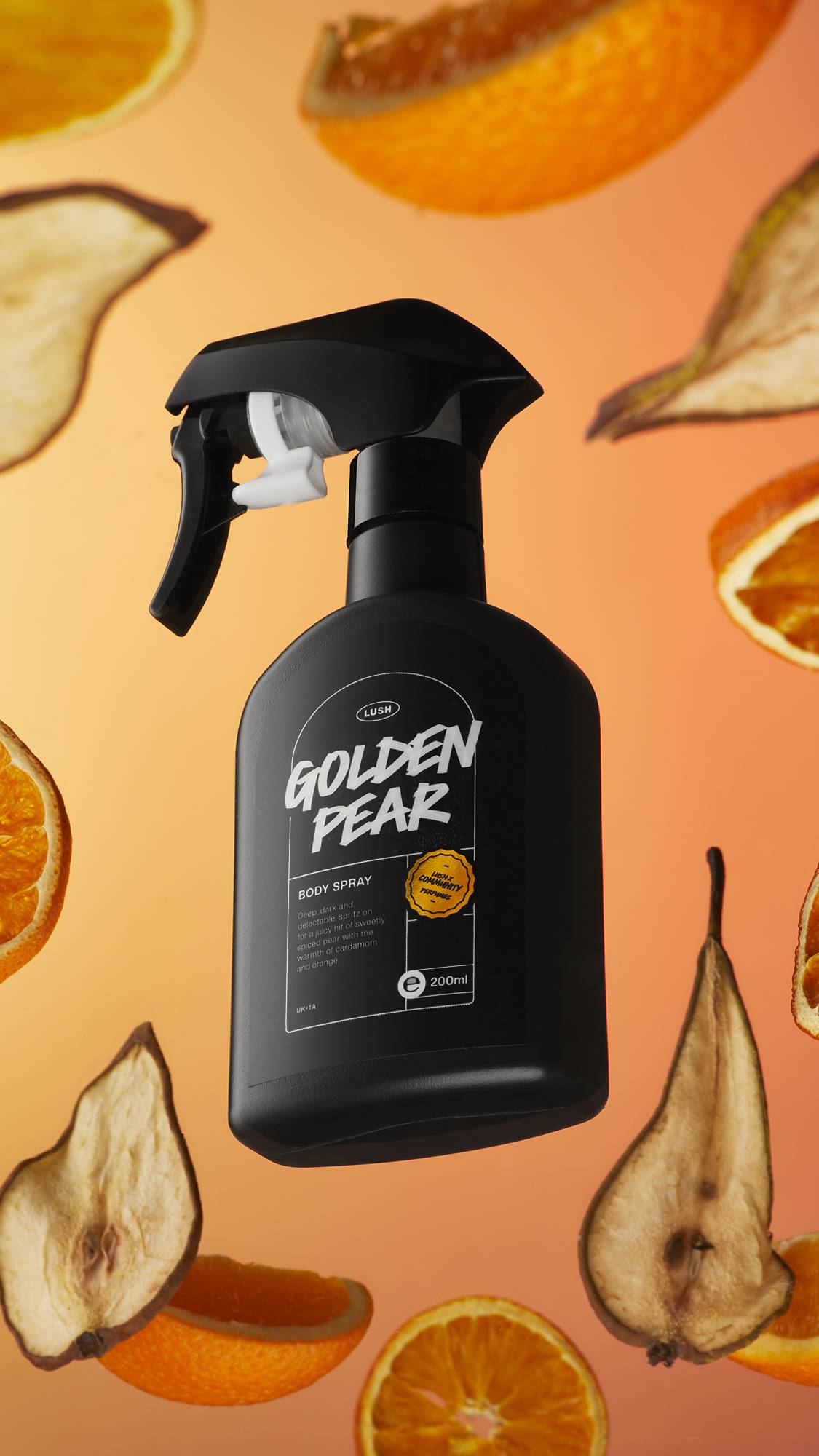 The black Golden Pear body spray body is in front of an orange background surrounded by dried pear and orange slices.