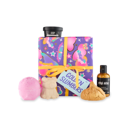 Golden Slumbers. A Square gift box wrapped in purple paper with pink, blue and orange patterns of clouds and butterflies, tied with a yellow ribbon and gift tag. Five included Lush products sit around the gift box. 