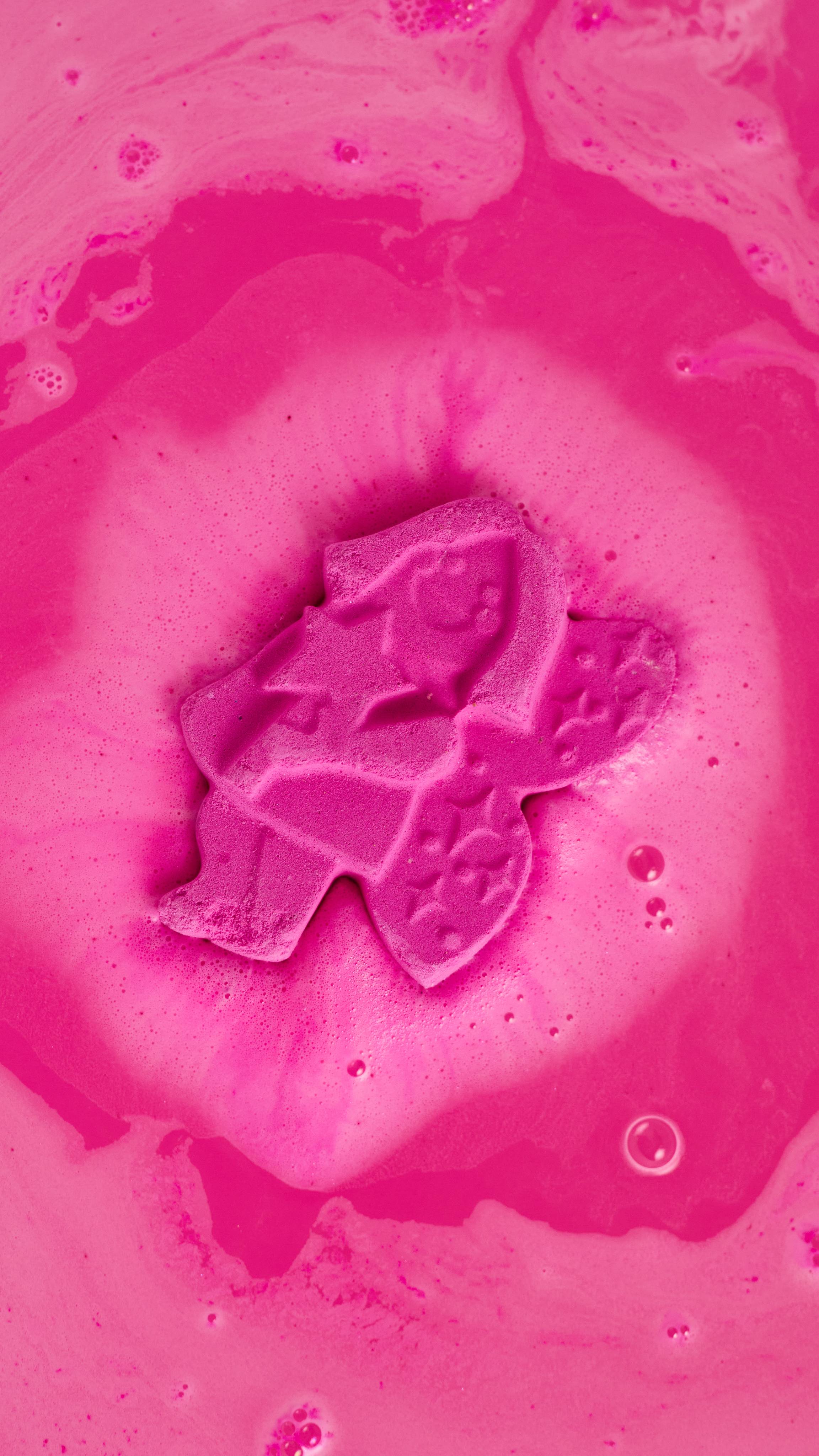 Groovy Fairy bath bomb is melting into the bath water creating layers of deep pink, foamy swirls.