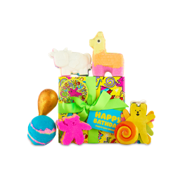 Happy Bathday. A bright yellow wrapped gift box with lime green ribbon and playful paper sits surrounded by six colourful Lush bathing products and extra decorations. 