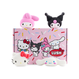 Lush x Hello Kitty and Friends gift set. A pink, cardboard gift box. It has a confetti-style sprinkle design with the four Hello Kitty character illustrations and the Lush logo. The four included bath bombs sit on and around the box,