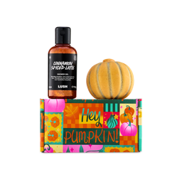 A bottle of shimmering brown "Cinnamon Spiced Latte" shower gel and an orange pumpkin-shaped bath bomb sit atop a colourful "Hey Pumpkin!" patterned gift box.