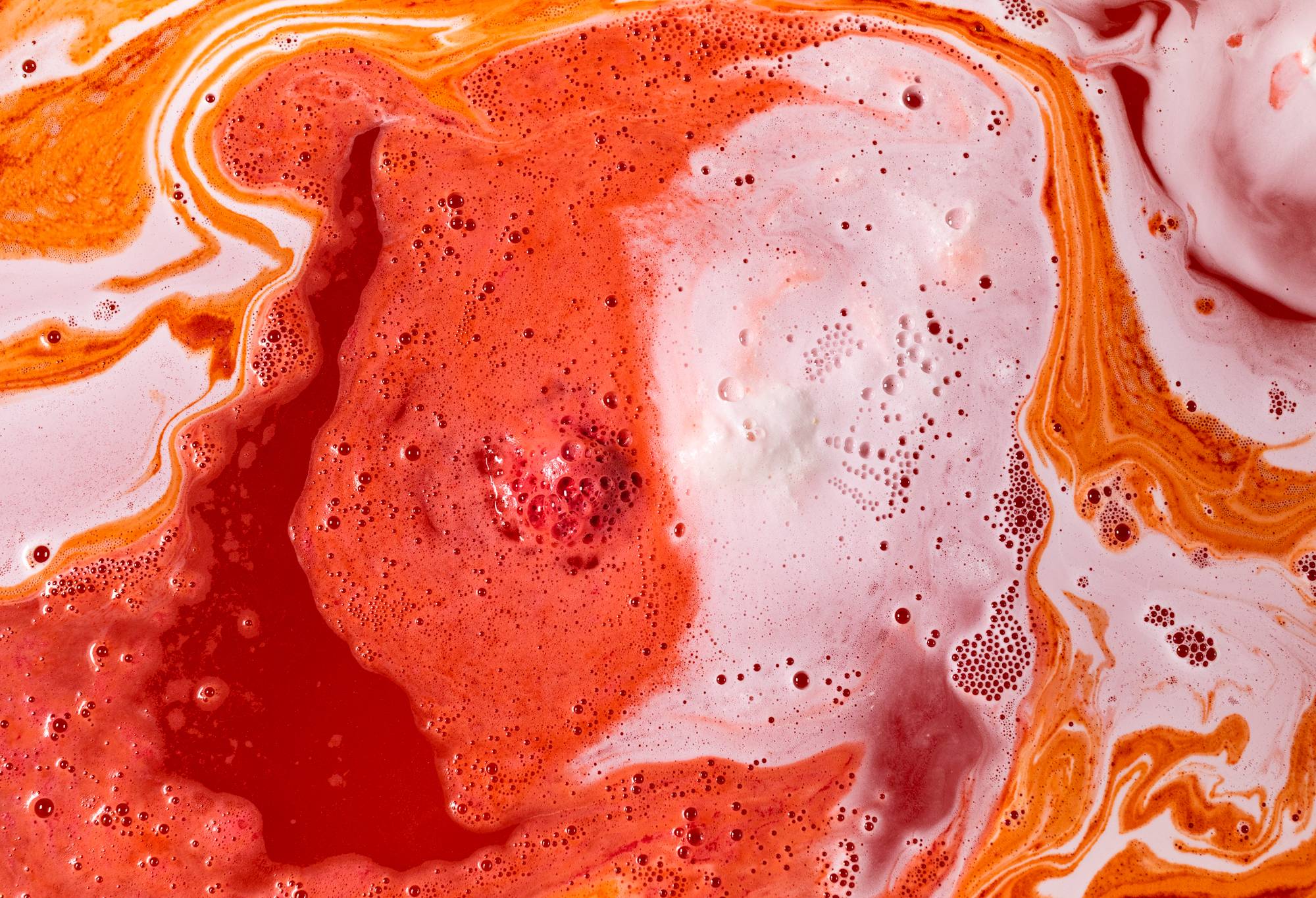 Human-Human Fruit bath bomb transforming waters into magnificent white, orange and red fizzing swirls.