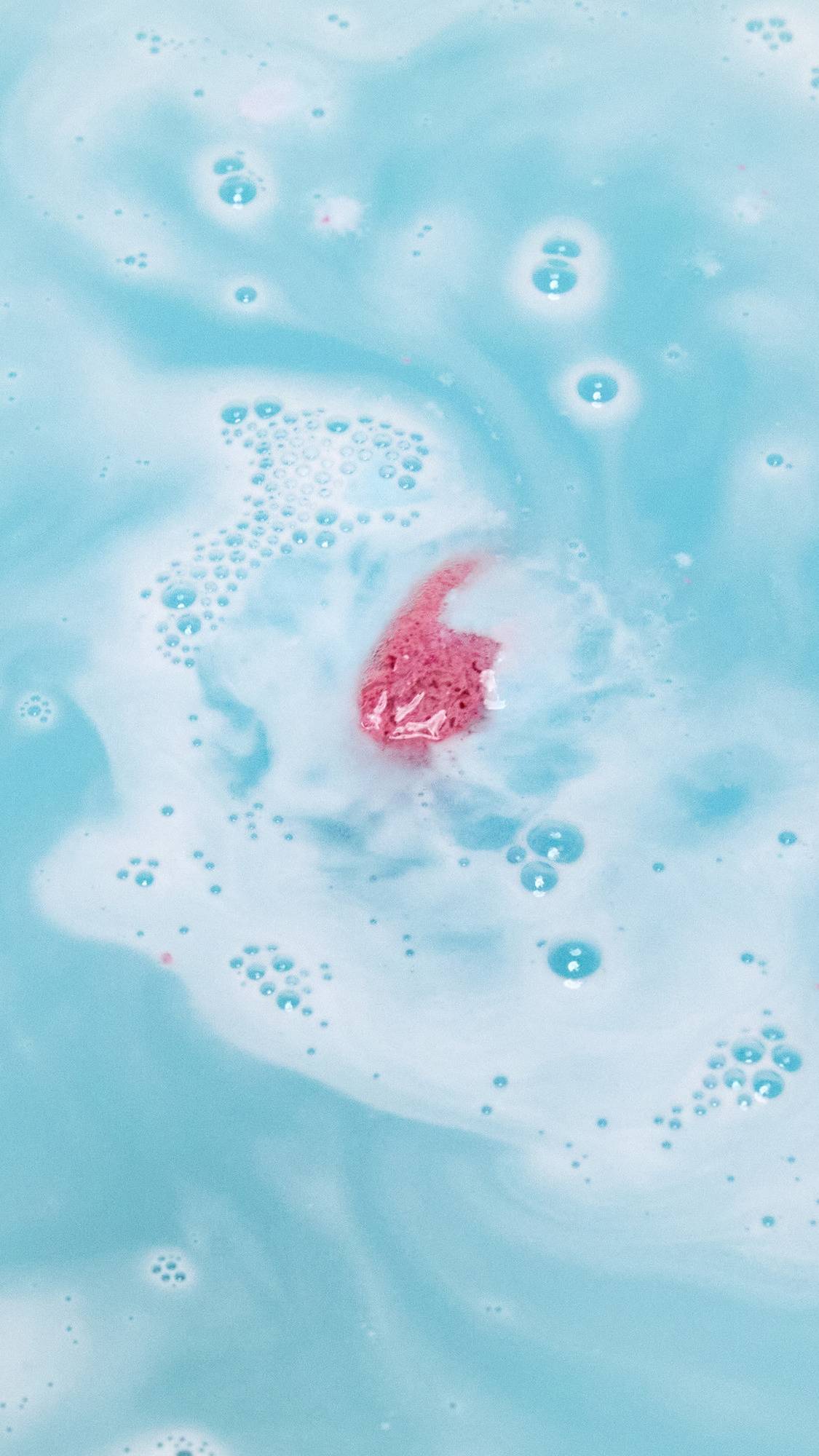 The Ickle Baby Bot bath bomb has fully dissolved leaving behind a mysterious glimpse of a surprise pink product floating on the crystal blue waters. 