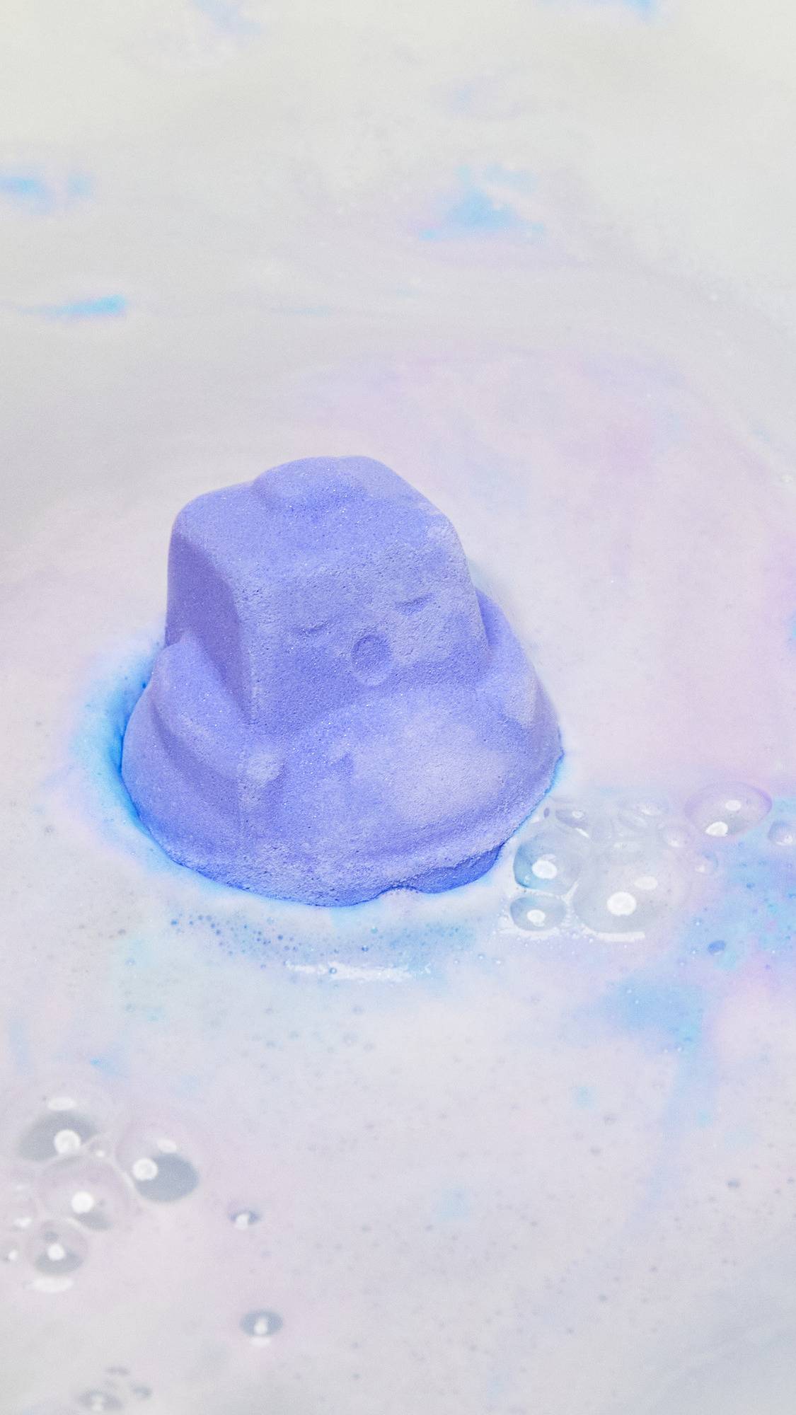 The Sleepy Bot bath bomb has been gently placed into the bath water and is beginning to give off subtle lavender foam.