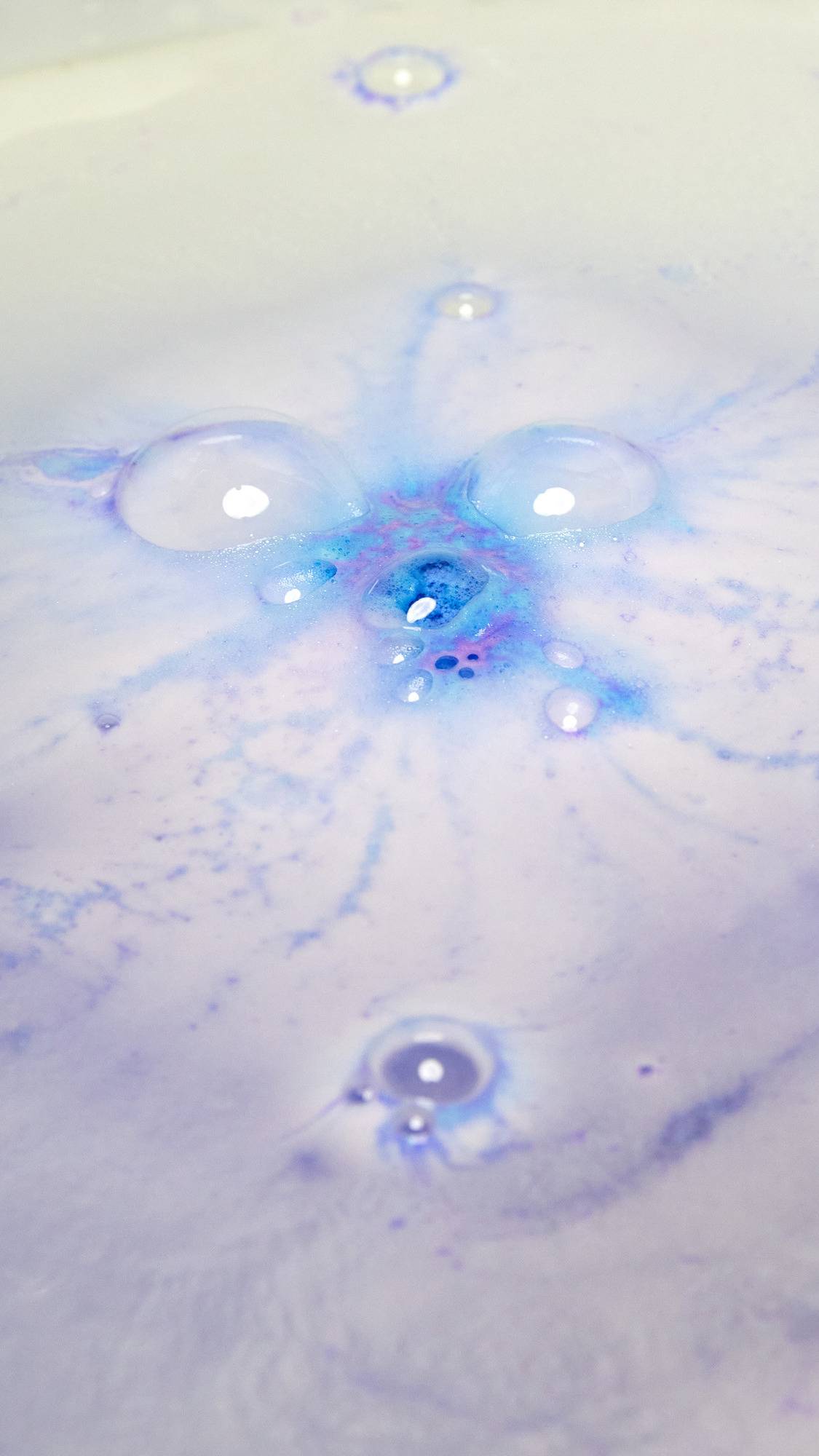 The Sleepy Bot bath bomb has completely dissolved in the water leaving behind silky, lavender-purple waters with a burst of deep purple foam in the centre.