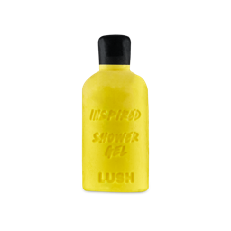 Inspired. A bright yellow solid shower gel bar shaped like a bottle, embossed with the words 'INSPIRED SHOWER GEL' and 'LUSH'. It features a moulded black top resembling a cap.
