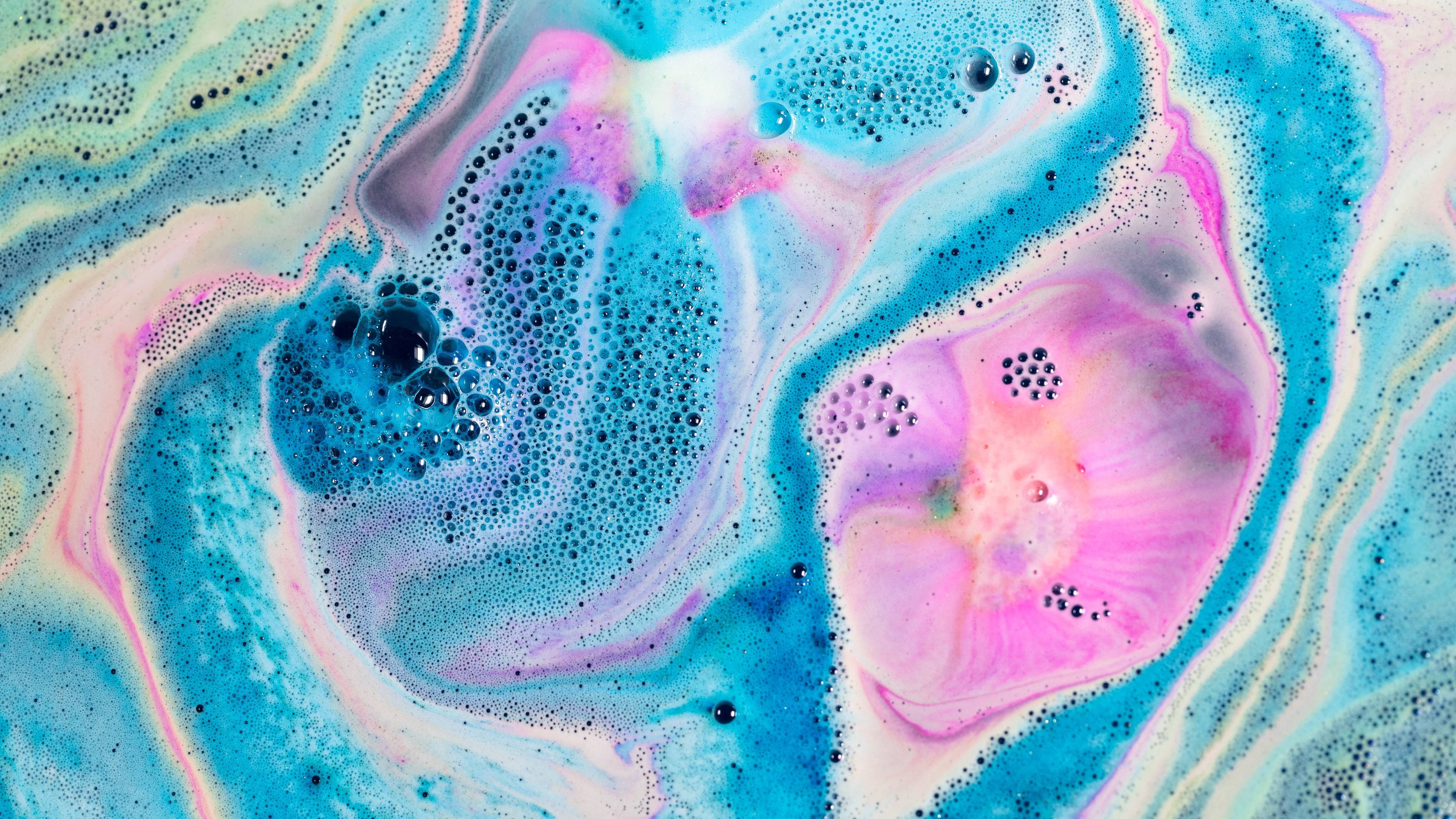 Bright blue, pink and white foam sit atop dark waters, creating a deep space effect. A myriad of bubbles complete this galaxy.