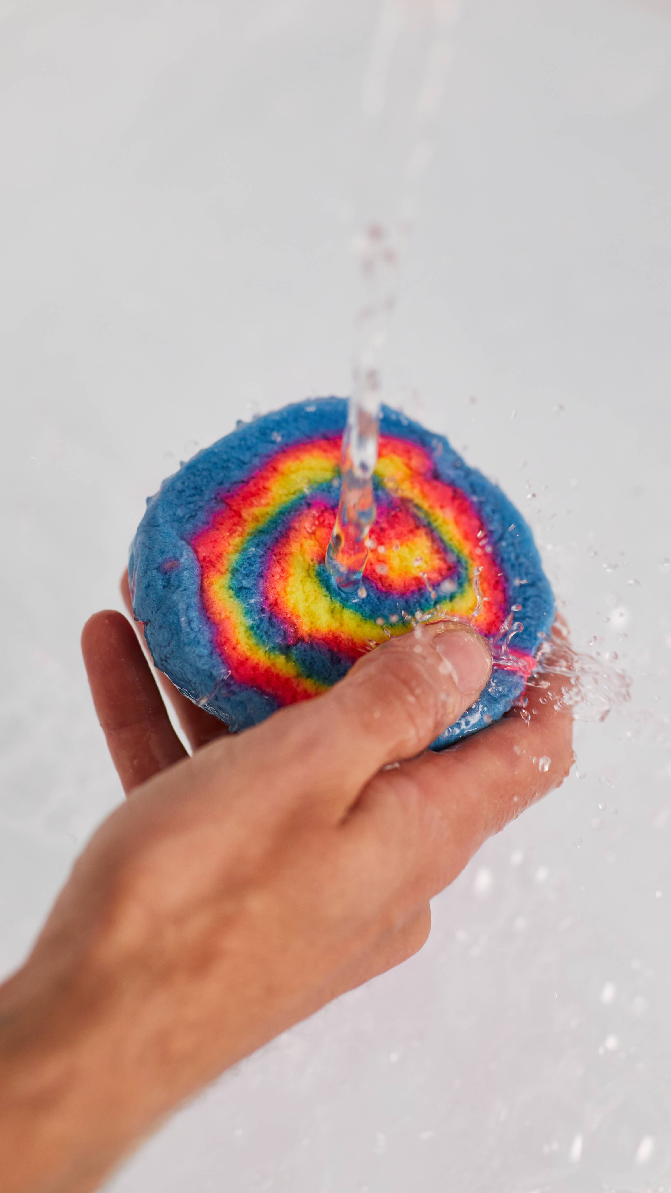 Image shows a close-up of the model's hand holding the Intergalactic bubble bar under running tap water.