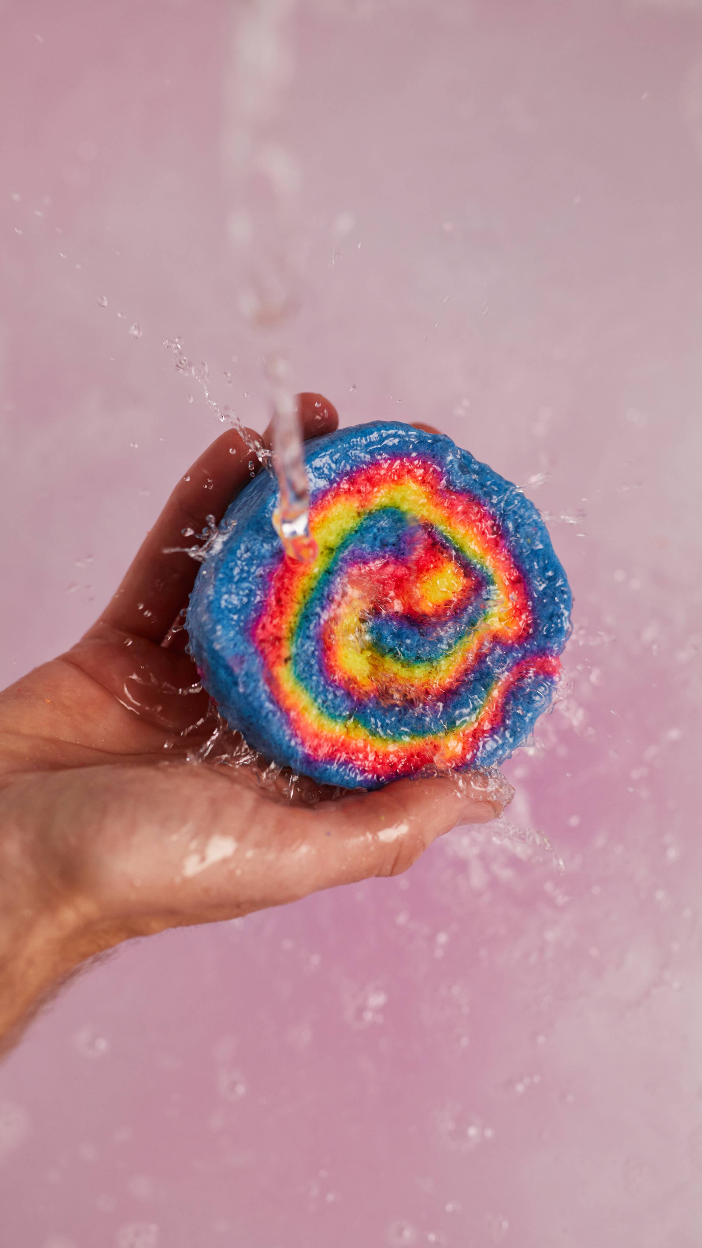 Image shows the model holding the Intergalactic bubble bar under running water as bubbles form below.