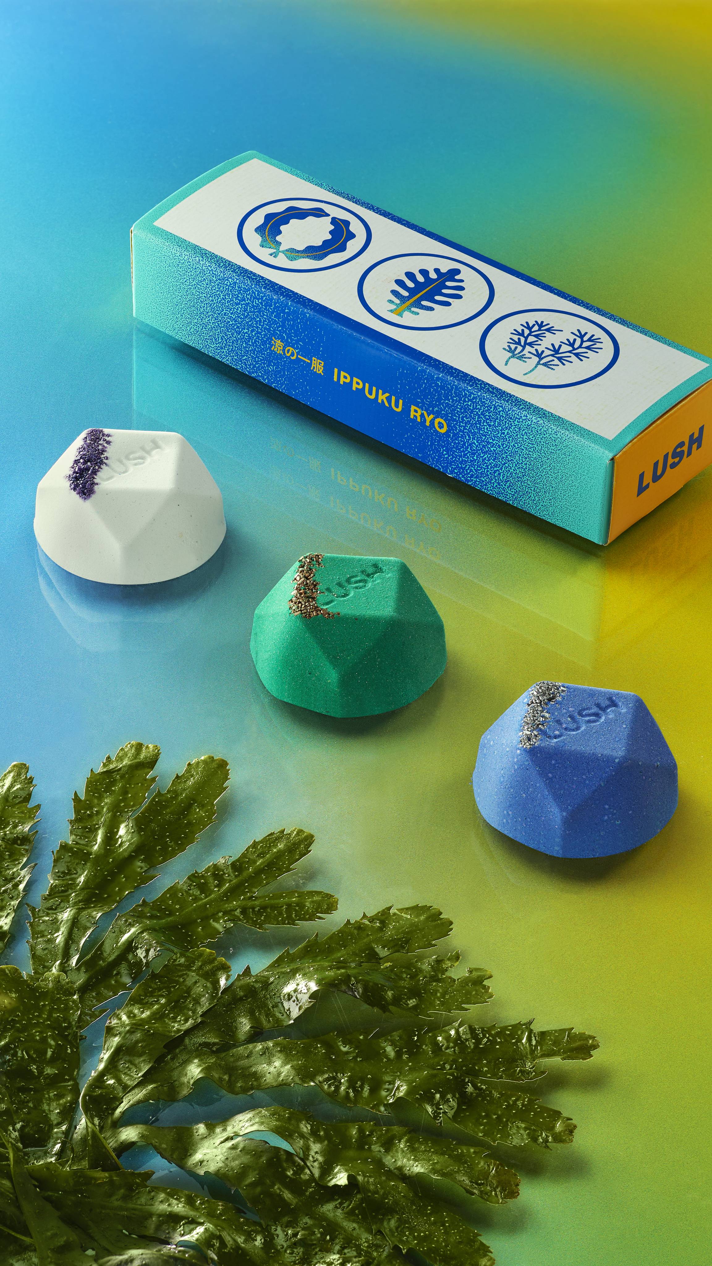 Three Ippuku cooling bath bombs in a line with seaweed on the left, and the box on the right on top of a blue-to-green gradient.