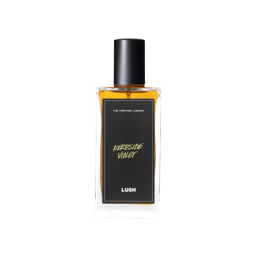 A glass perfume bottle filled with amber liquid. A black label reads 'The Perfume Library' and 'Kerbside Violet'.