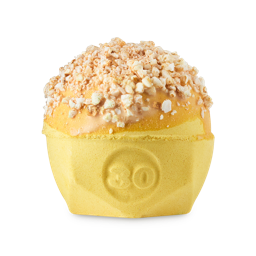 Let The Good Times Roll. A spherical bath bomb with a flat, geometric base. The product is a bright yellow colour with the number "30" embossed on the side. The top has a coating of solid cocoa butter and crumbled popcorn pieces.