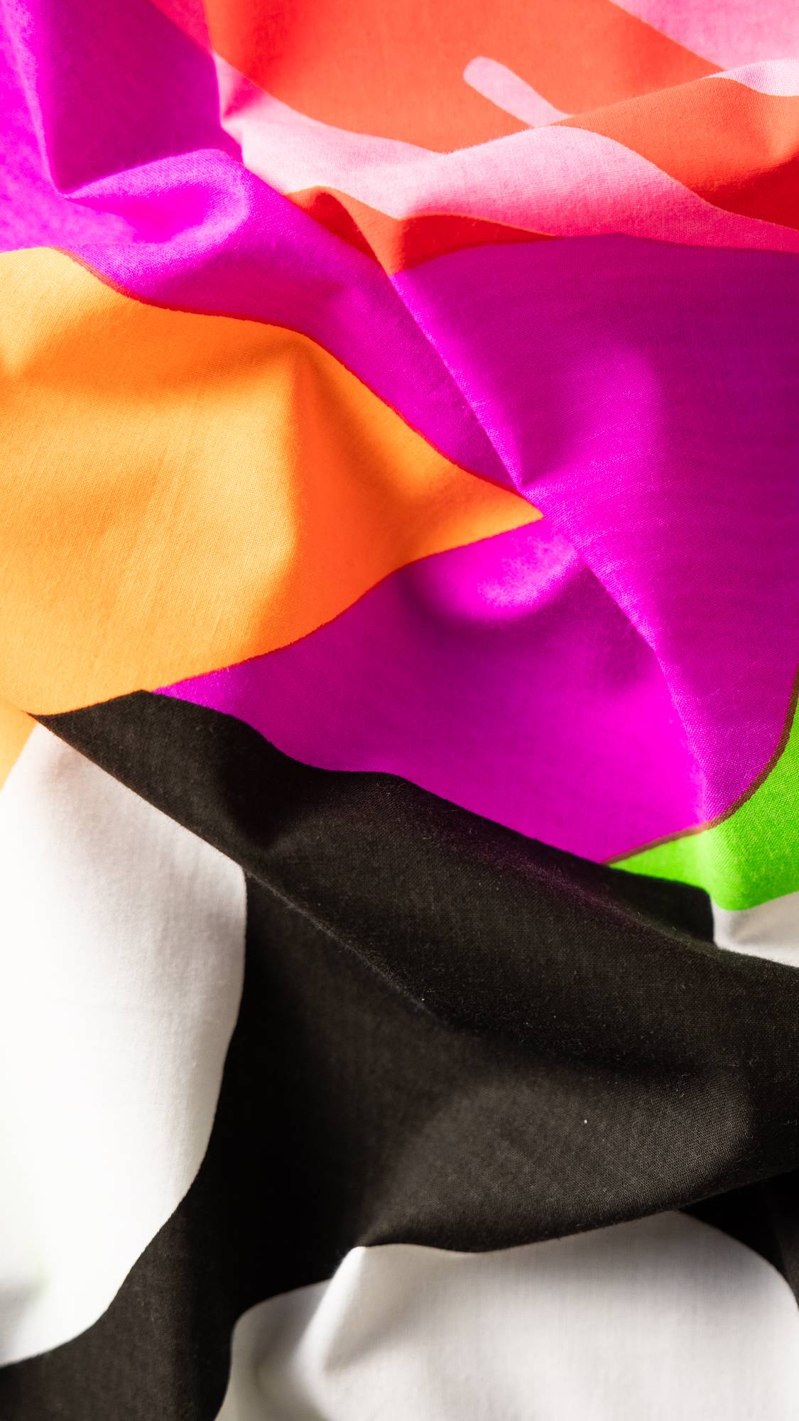 Image shows a super close-up of the Loose Ends knot wrap. Bold blocks of black, white, pink, orange and green.