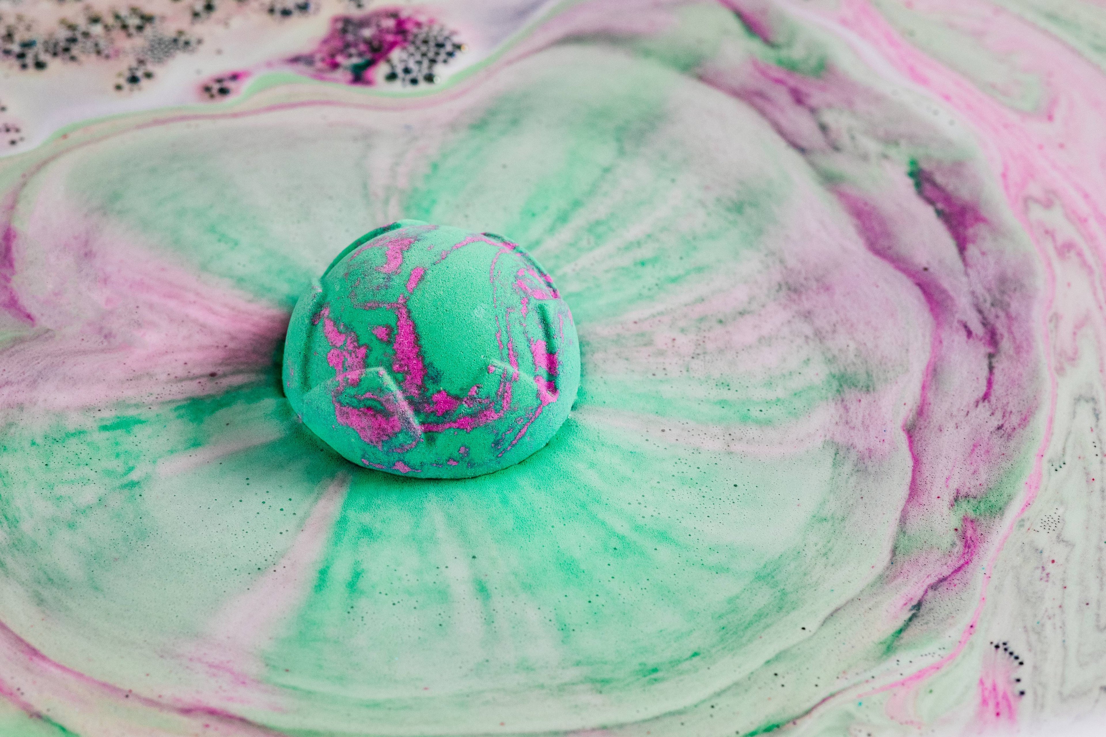 Lord of Misrule bath bomb floats, meting among a foamy sea of enchanting pink and green swirls. 