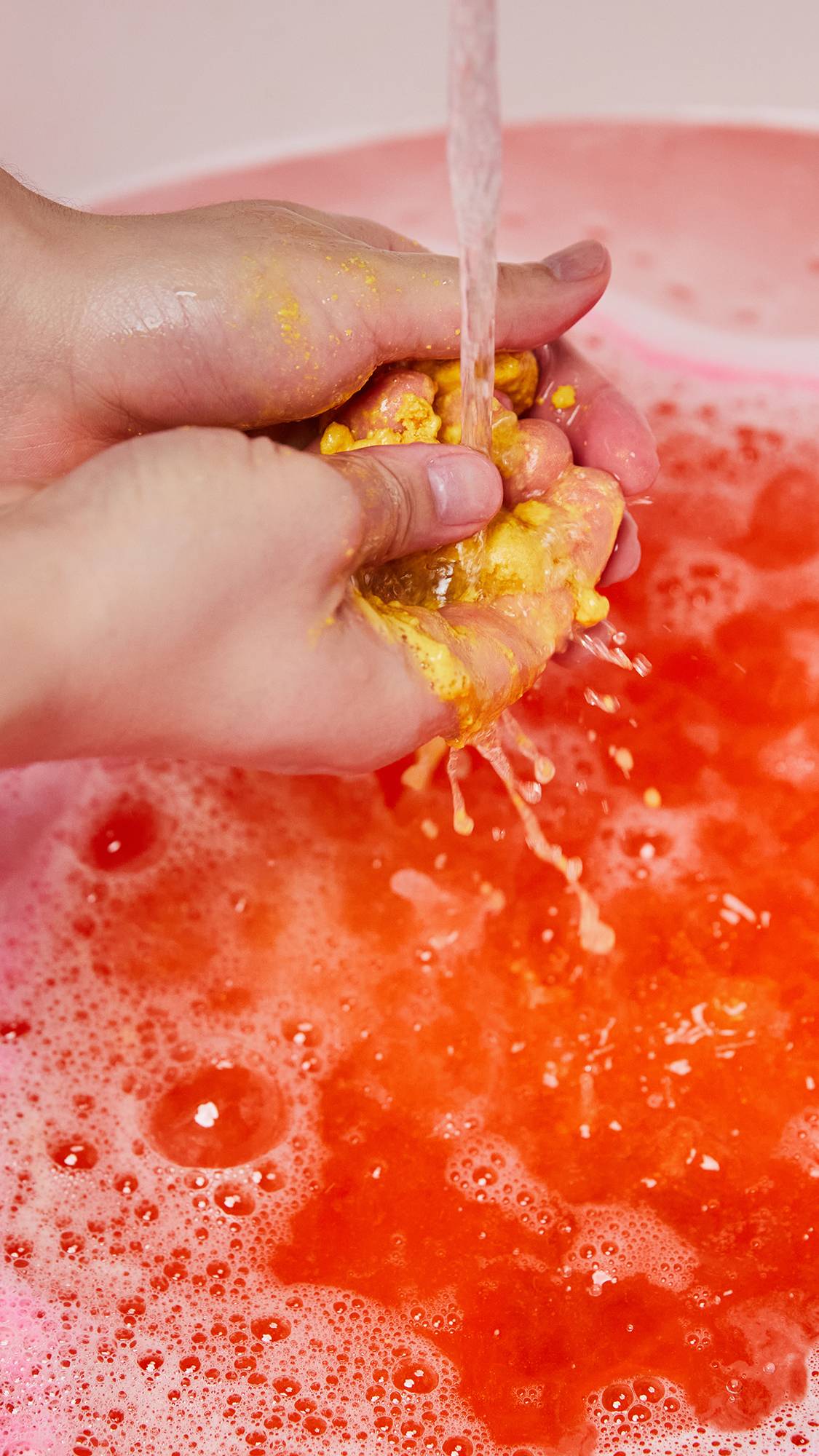 The image shows the model using the burger patty bubble bar as they crumble it under running water.
