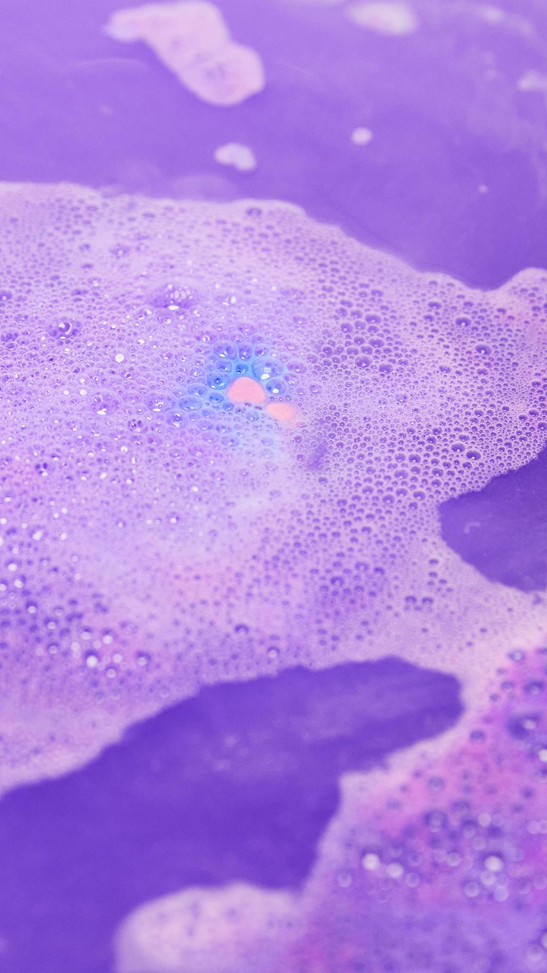 The Love Potion bath bomb is slowly fizzling away leaving deep, pastel purple water and delicate foam.
