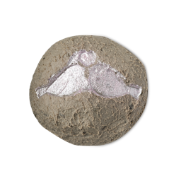 The round Lovey Dovey facial cleanser features a textured, brownish-grey base topped with a shimmering, silvery design of two birds kissing under a heart against a light background.