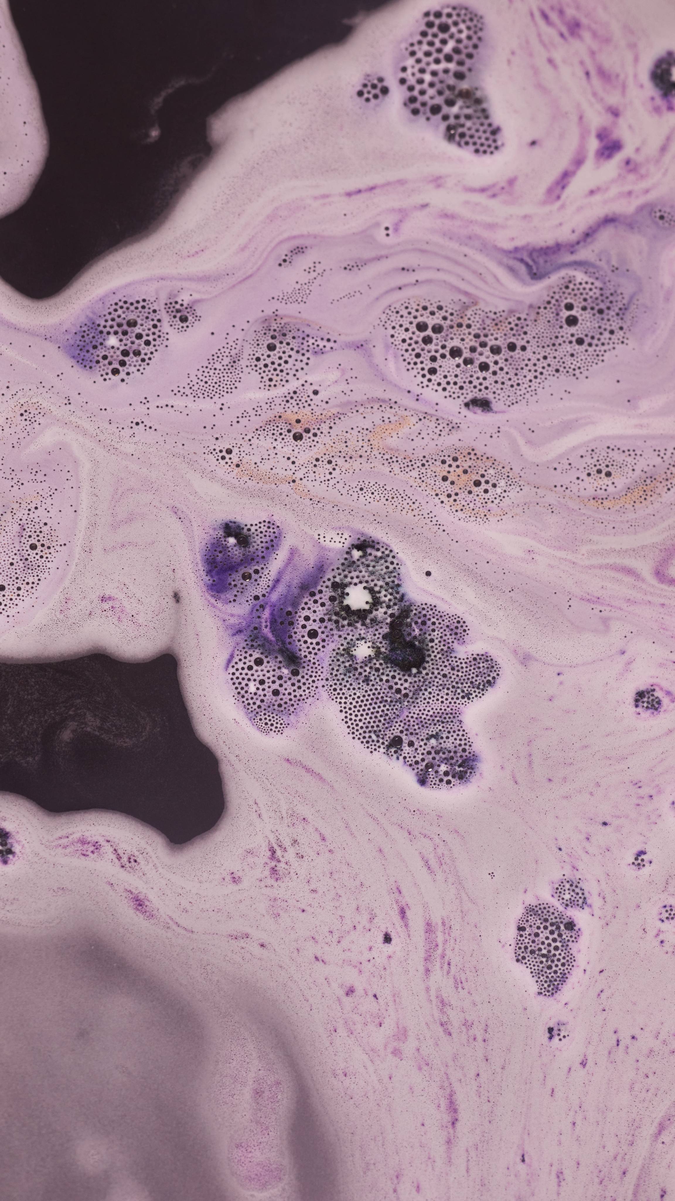 The Lump of Coal bath bomb has fully dissolved leaving a velvety sea of almost-black, deep purple ripples.