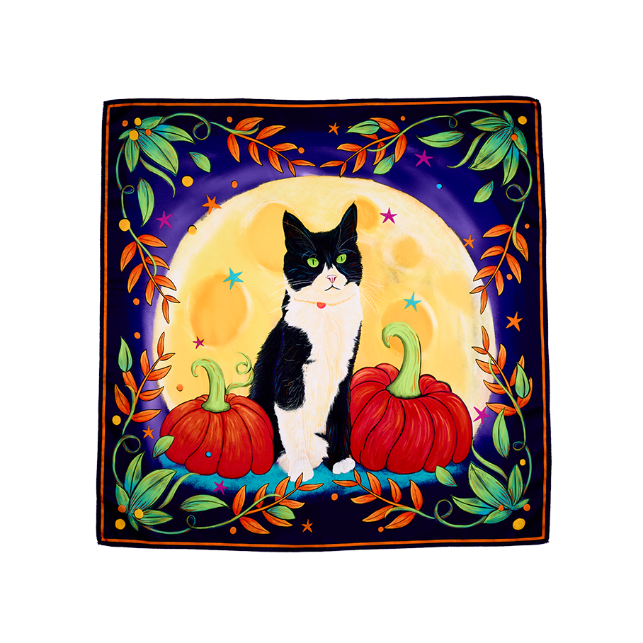 Luna The Cat. The image shows a square fabric wrap with a midnight blue background and a large full moon. It features a black-and-white cat sitting between two pumpkins, and a border of colourful leaves and stars.