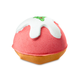 Lush Pudding. A Christmas pudding-shaped bath bomb with a pinkish-red dome, beige base, and white icing dripping over the top topped with a green holly leaf and red berry.