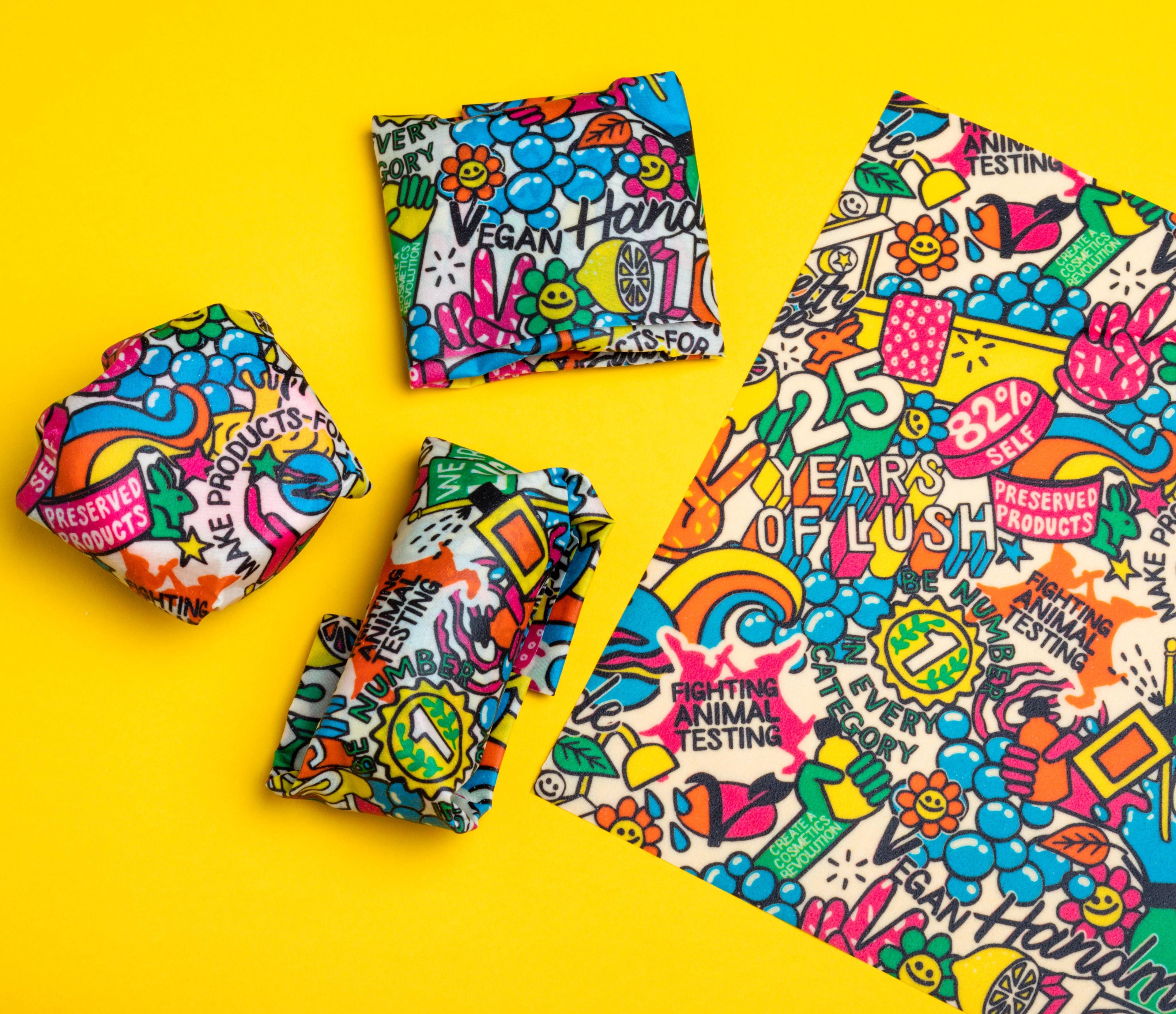 A brightly coloured, cartoon design Lush Wax Wrap is laid out flat, while others have been used to wrap up various items.
