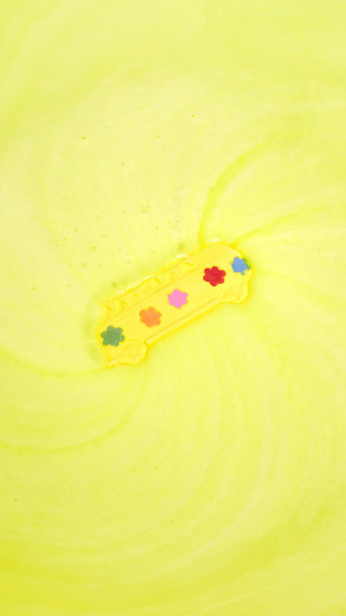 The Magic Bus bath bomb is sat in the bath water, still intact, giving off a thick velvety blanket of canary-yellow foam. 