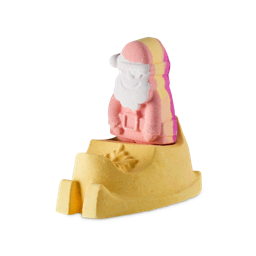 Magical Santa Sleigh. A two-part, festive Lush bath bomb comprised of a lower, golden-yellow sleigh-shaped bath bomb with a second, colourful, Santa-shaped bath bomb sitting inside it.