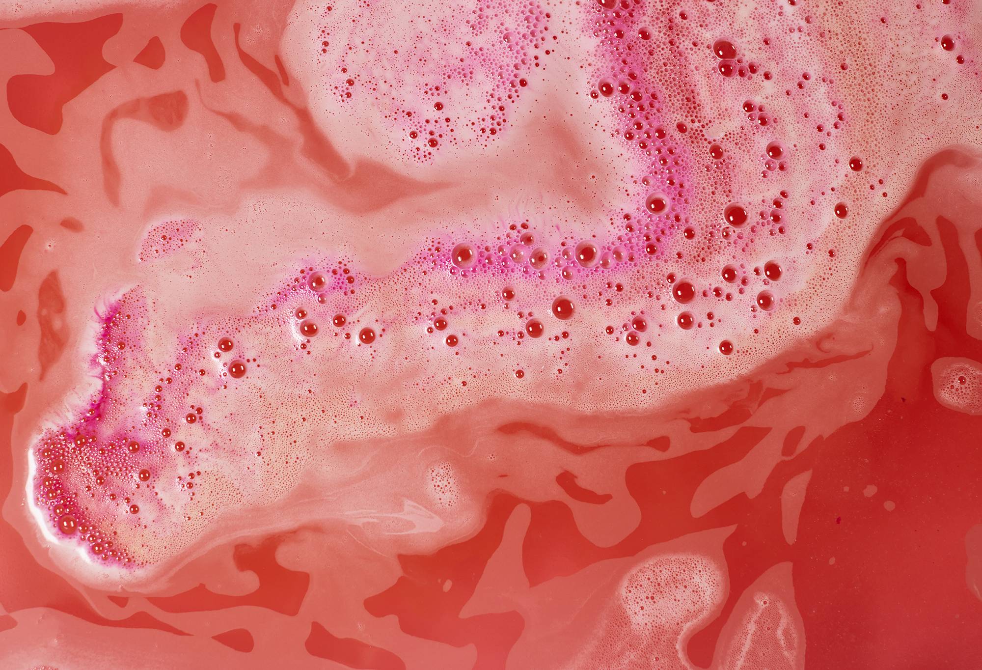 Magical Santa bath bomb has dissolved leaving thick, foamy pink and red swirls. 