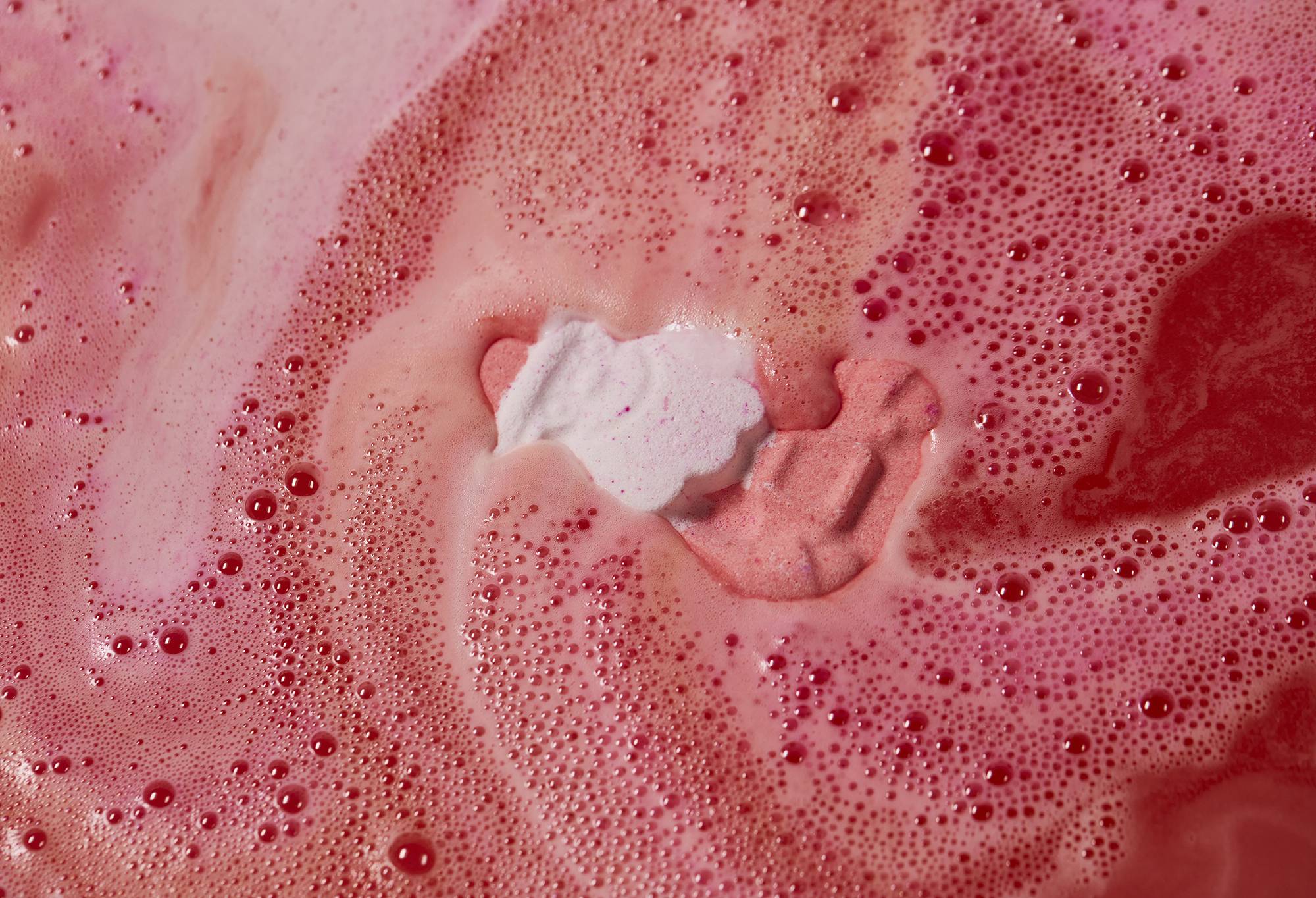 Magical Santa bath bomb has nearly been engulfed by the thick, foamy, red and pink water. 