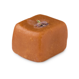 Maple Sugar. A solid facial sugar scrub. The product is a deep, caramel-brown colour and has been shaped to resemble a soft, rounded cube. A flower has been pressed into the top of the product. 