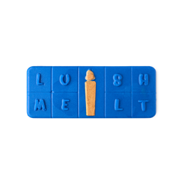 A rectangular, segmented Menorah Melt in deep royal blue spells "LUSH MELT" with raised letters. The center column features a golden orange shape resembling a lit candle or flame, set against a light grey background.