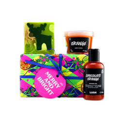 A Lush "Merry and Bright" gift box wrapped in colourful festive paper with a blue ribbon and pink tag, flanked by Chocolate Orange shower gel, Orange body scrub, and a green reindeer soap