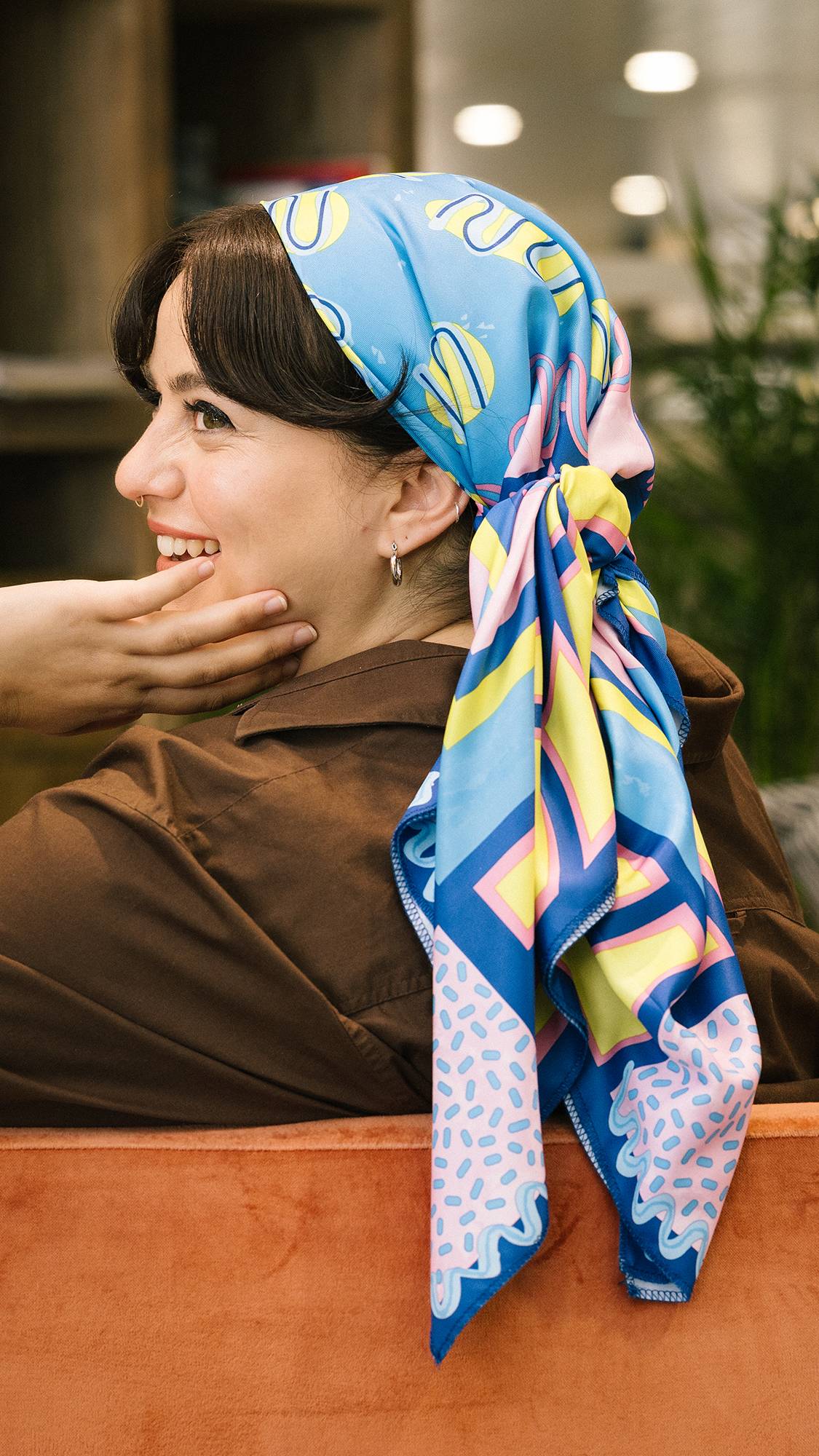 Image shows model wearing Metamorphosis knot wrap as a stylish head wrap with the striking patterns trailing down her neck.