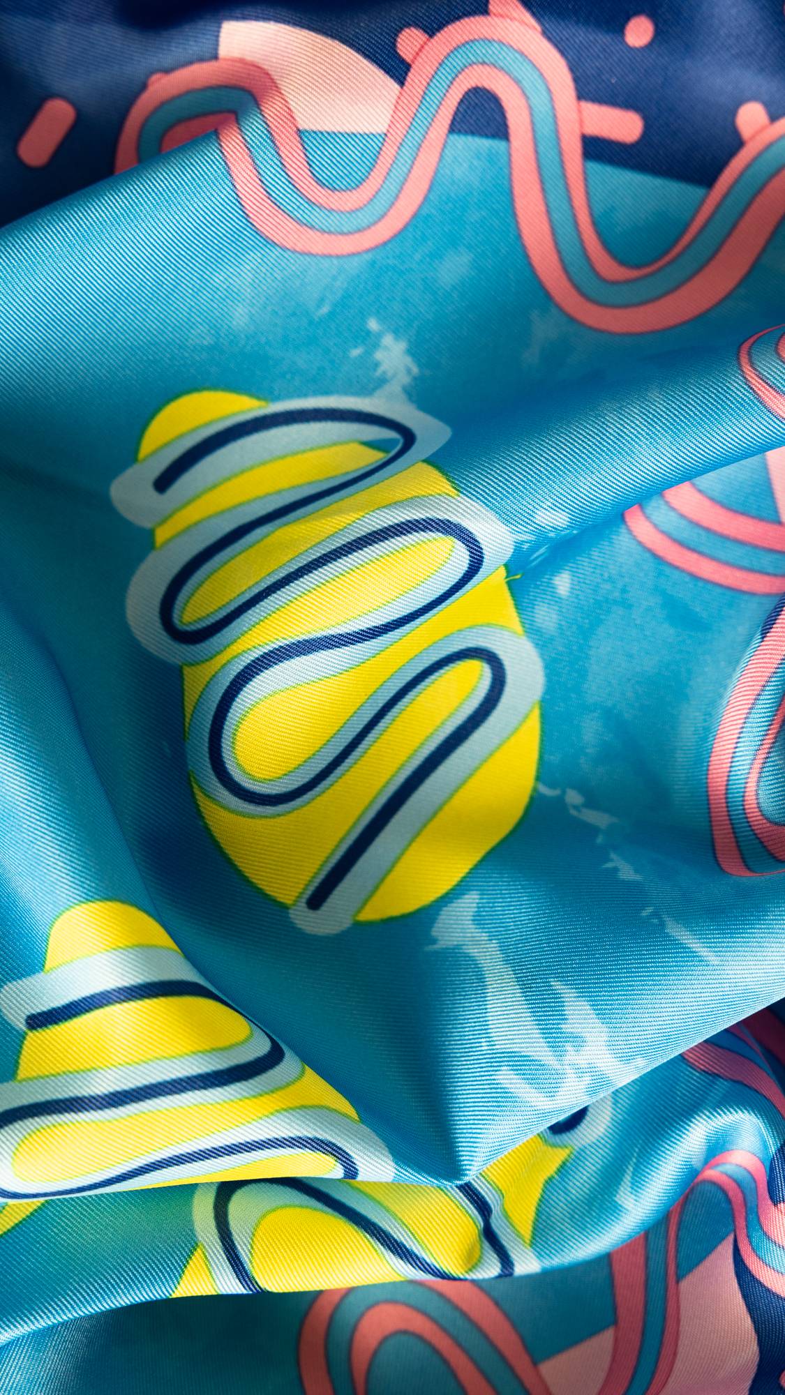 Image shows a super close-up of the Metamorphosis knot wrap. Image is focused on a large yellow blob with blue swirls on top. 