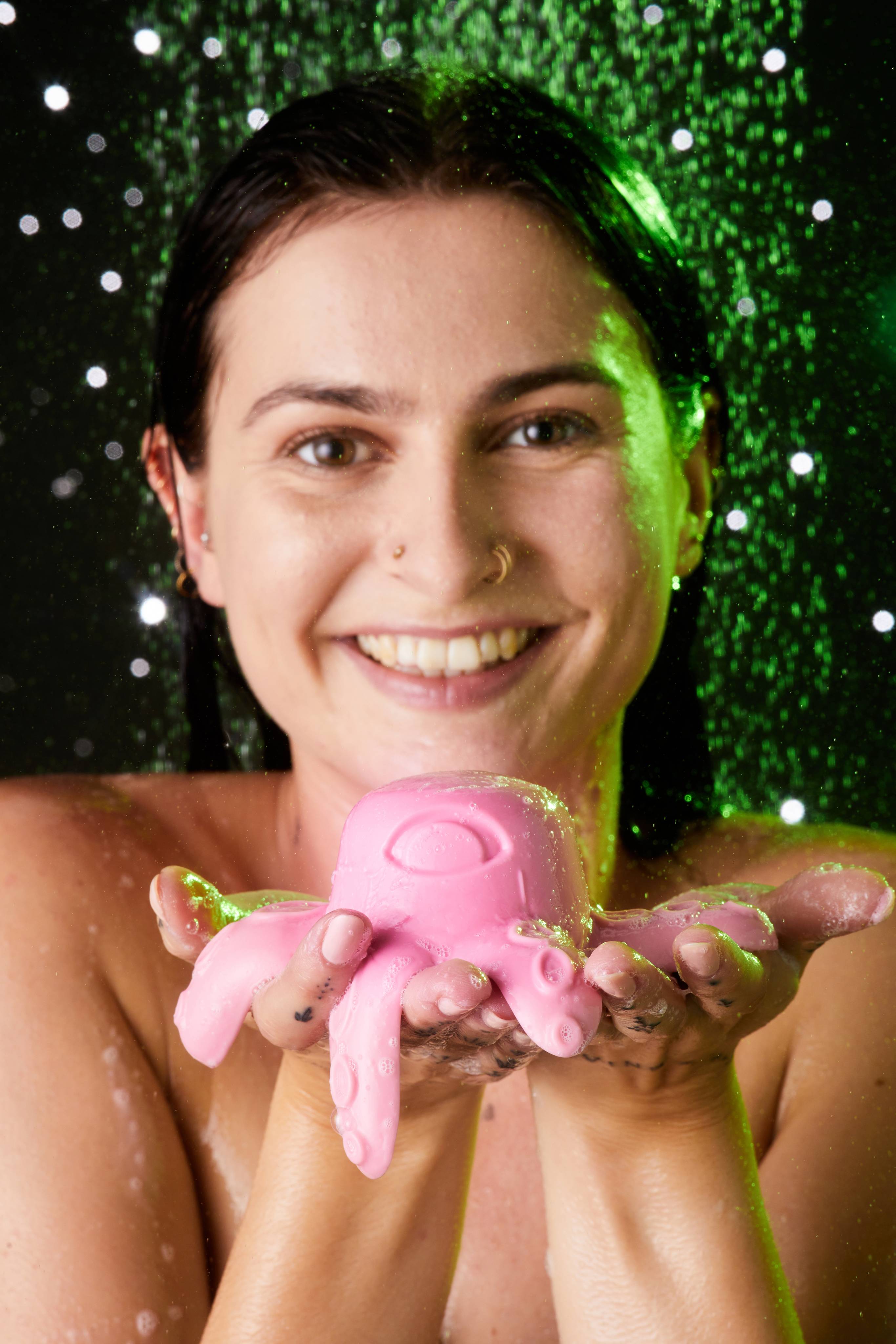 A front shot with the model who smiles at the camera as they hold the Monster Octopus shower jelly which spans both hands.