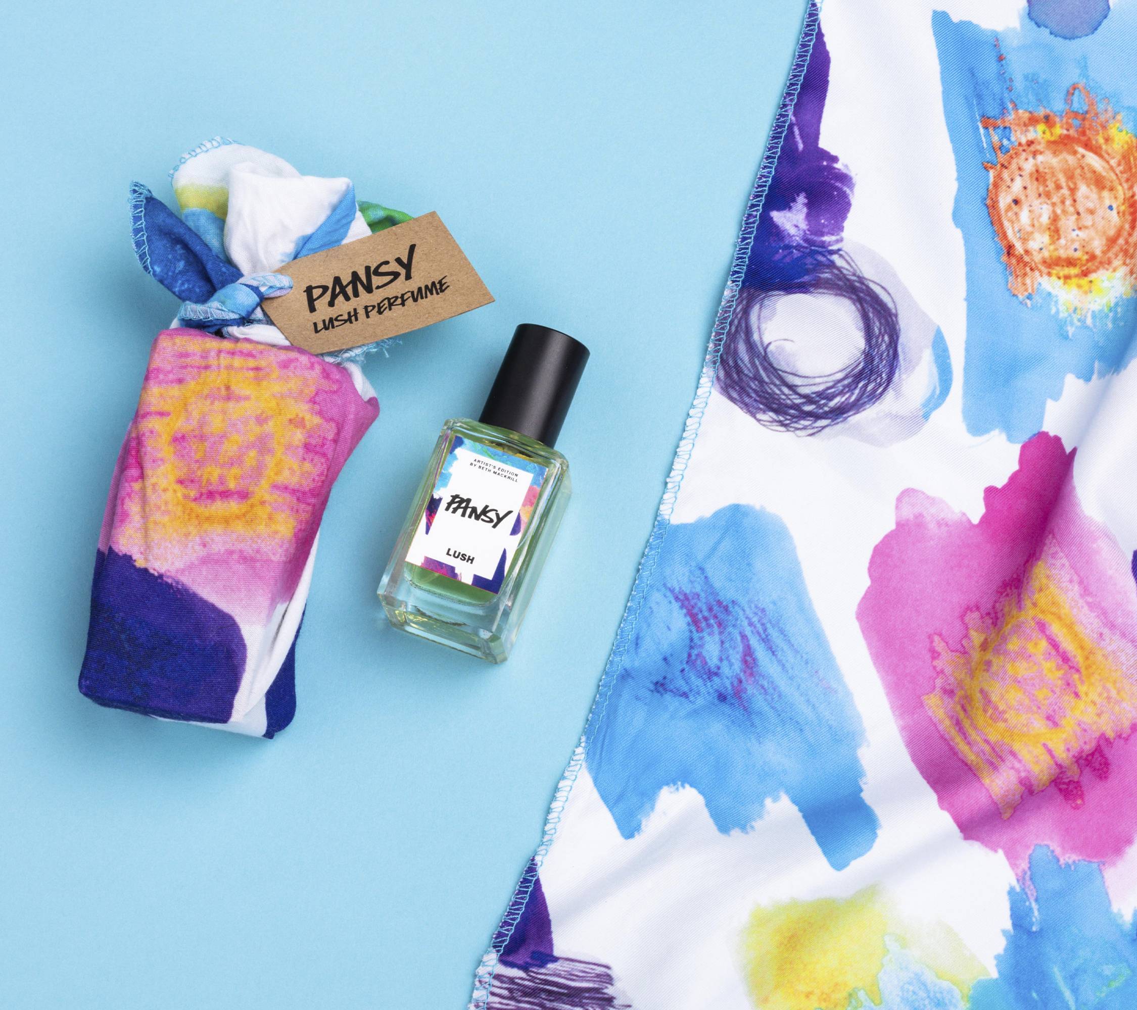 Pansy lies on a light blue background, alongside its two elements: a small bottle of Pansy perfume and a colourful knot wrap.
