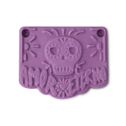 Papel Picado Morado soap. The image shows a smooth, pastel purple rectangular soap. Its surface features an embossed sugar skull and the text 'AMOR ETERNO', all in a stylised, decorative design resembling a bunting flag.