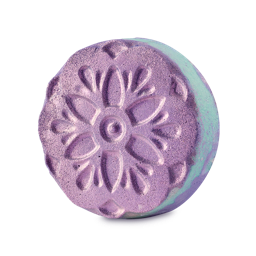Prakash. A round, disc-shaped bath bomb with an embossed floral pattern on its purple top. The sides are marbled with pastel green and purple, and the surface has a shimmering lustre.